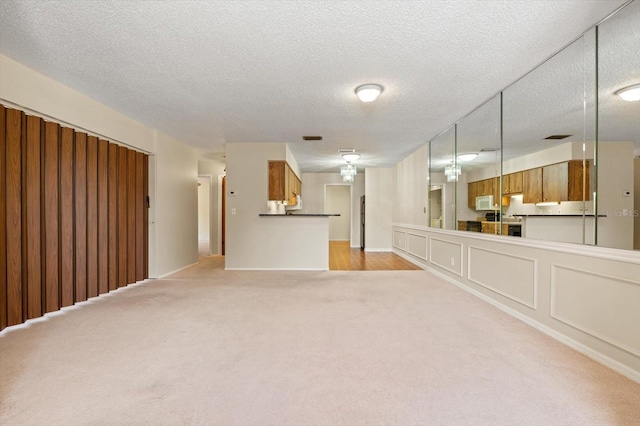 unfurnished living room featuring light colored carpet and a textured ceiling