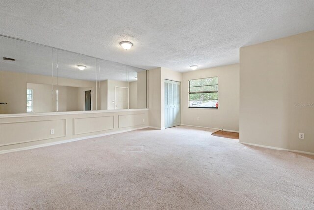 carpeted spare room with a textured ceiling