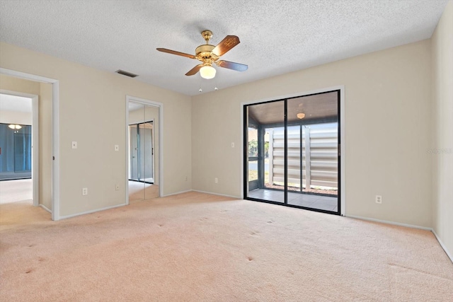 empty room featuring light carpet, a textured ceiling, and ceiling fan