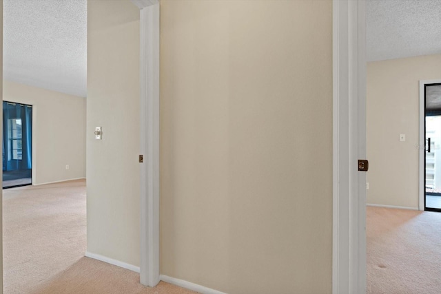 hallway featuring light carpet, a wealth of natural light, and a textured ceiling