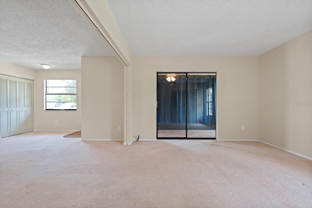 unfurnished room featuring light colored carpet and a textured ceiling