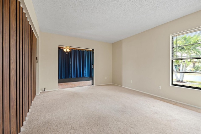 unfurnished room with light colored carpet and a textured ceiling