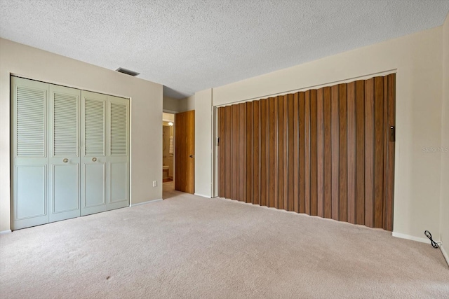 unfurnished bedroom with a closet, a textured ceiling, and light colored carpet