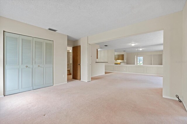 interior space featuring light colored carpet and a textured ceiling