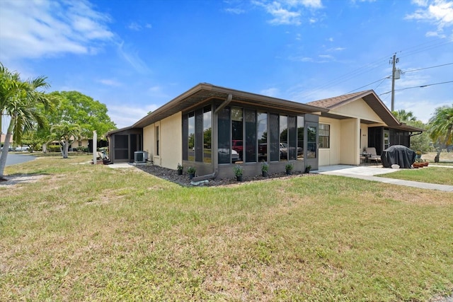 back of property with a sunroom, central air condition unit, and a lawn