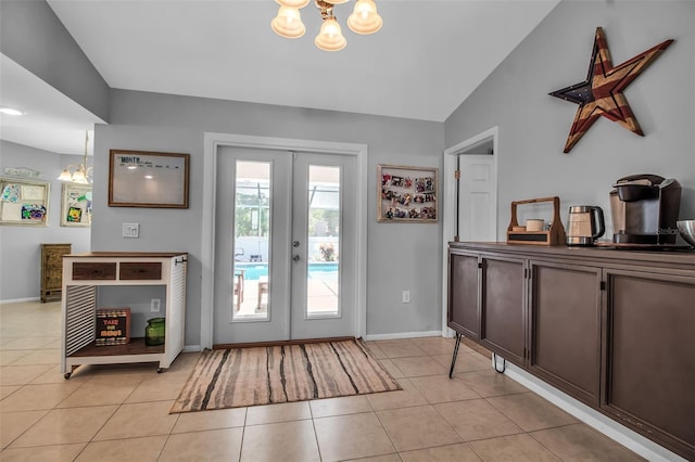 doorway to outside featuring lofted ceiling, french doors, an inviting chandelier, and light tile patterned flooring