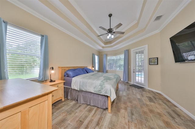 bedroom with access to outside, crown molding, ceiling fan, light wood-type flooring, and a tray ceiling