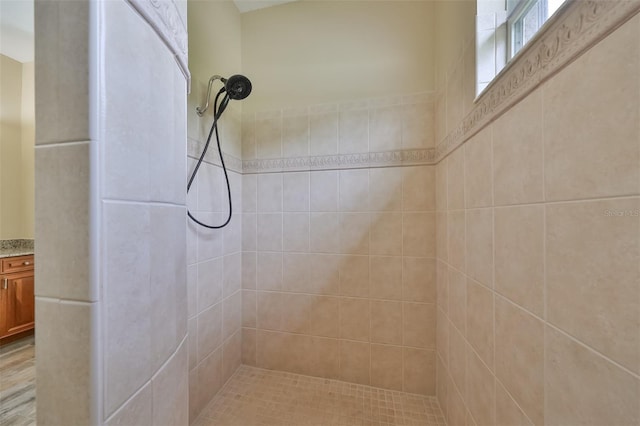 bathroom featuring hardwood / wood-style floors, vanity, and a tile shower