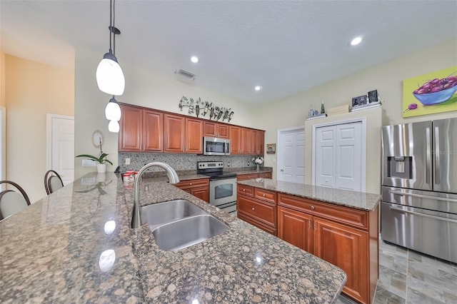 kitchen with pendant lighting, sink, a kitchen bar, kitchen peninsula, and stainless steel appliances