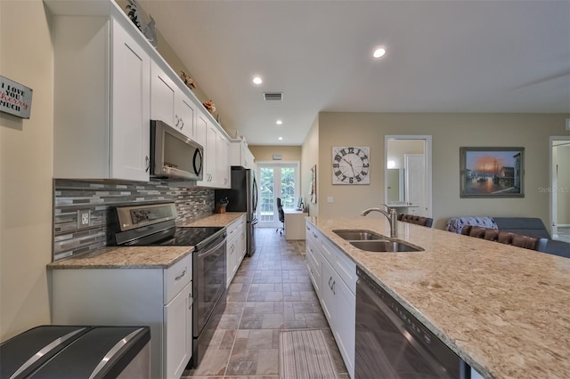 kitchen featuring white cabinetry, sink, stainless steel appliances, light stone counters, and backsplash