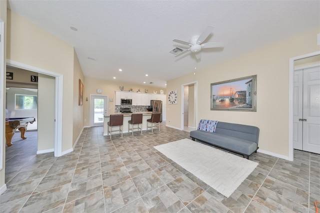 living room with ceiling fan, a textured ceiling, and pool table