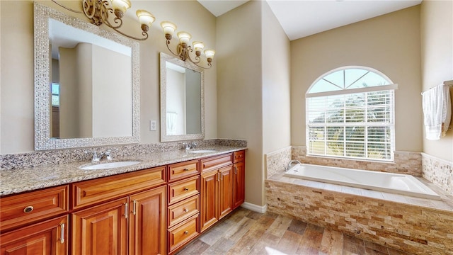 bathroom with tiled bath, vanity, a healthy amount of sunlight, and hardwood / wood-style flooring