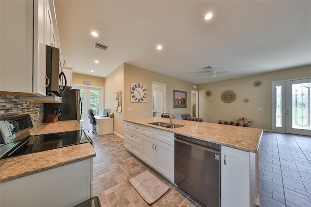 kitchen featuring light stone countertops, sink, a kitchen island with sink, white cabinets, and black appliances