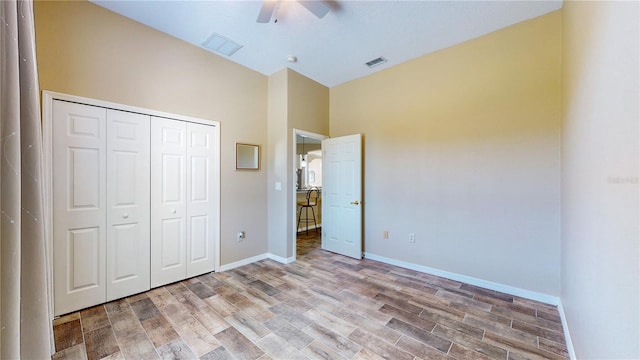 unfurnished bedroom featuring a closet, wood finished floors, visible vents, and baseboards