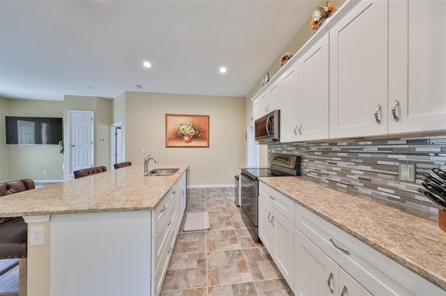 kitchen with a sink, stainless steel microwave, backsplash, a kitchen bar, and range with electric stovetop