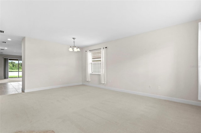 carpeted empty room featuring a notable chandelier