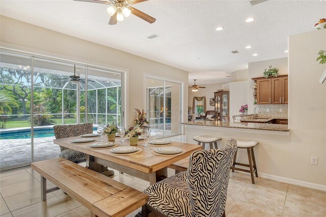 tiled dining room featuring a textured ceiling, sink, and ceiling fan