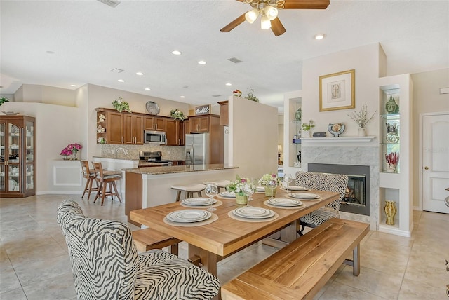 tiled dining space featuring a high end fireplace and ceiling fan