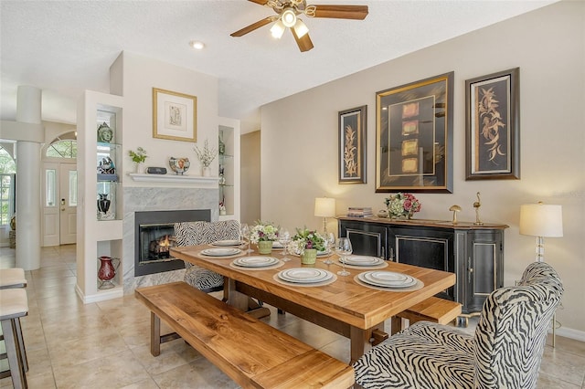 tiled dining room with a textured ceiling, a premium fireplace, and ceiling fan