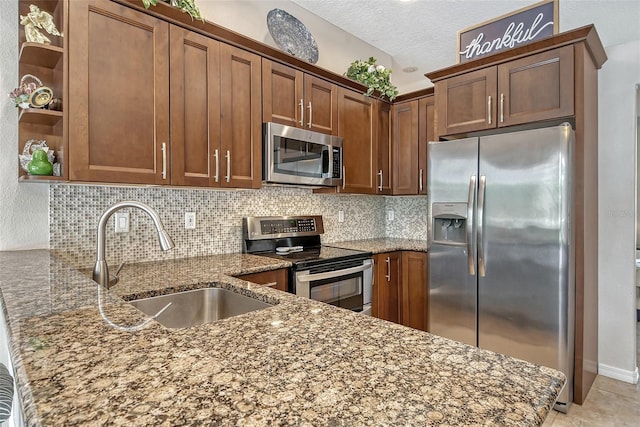 kitchen featuring light tile patterned flooring, a textured ceiling, stainless steel appliances, decorative backsplash, and sink