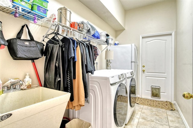 clothes washing area with sink, light tile patterned flooring, and washing machine and clothes dryer