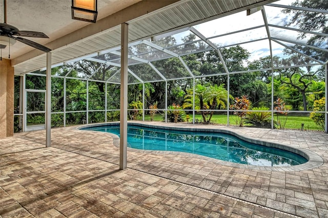 view of swimming pool featuring glass enclosure, ceiling fan, and a patio area