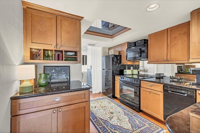 kitchen featuring dark stone countertops, light hardwood / wood-style flooring, and black appliances