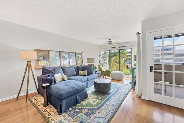 living room featuring wood-type flooring, a textured ceiling, and ceiling fan