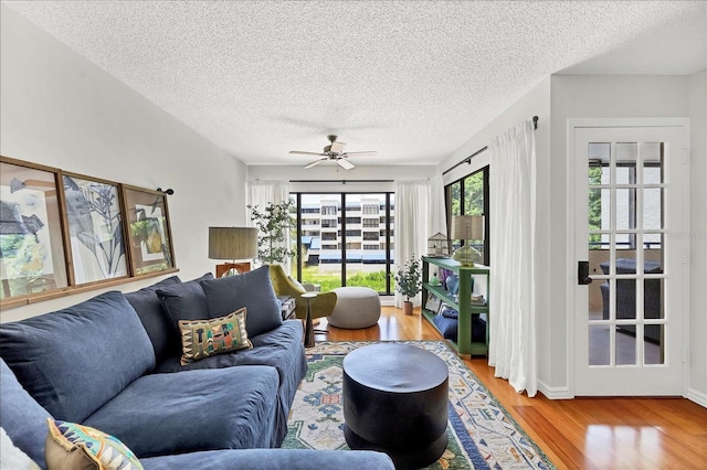 living room featuring ceiling fan, a textured ceiling, and hardwood / wood-style flooring