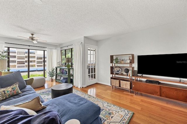 living room with hardwood / wood-style floors, a textured ceiling, and ceiling fan