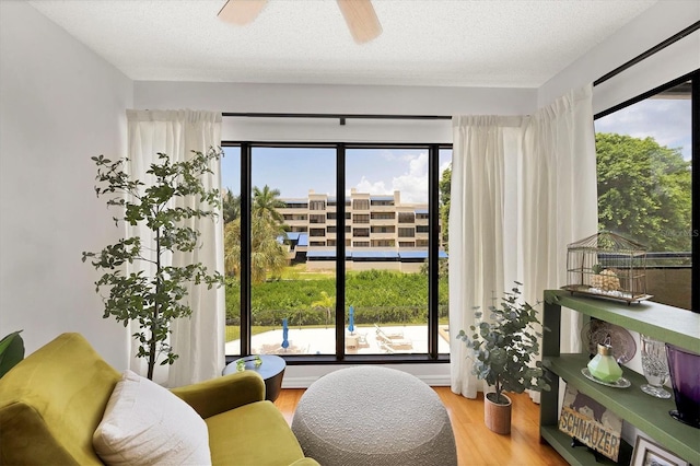 sitting room with ceiling fan, hardwood / wood-style floors, and a textured ceiling