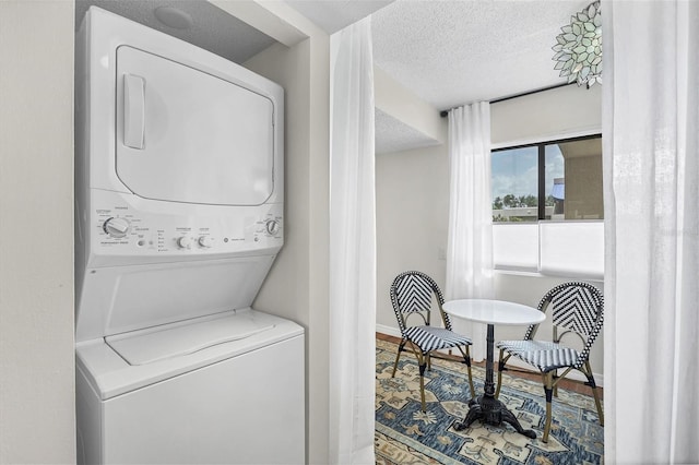 laundry room with a textured ceiling, hardwood / wood-style flooring, and stacked washer and clothes dryer