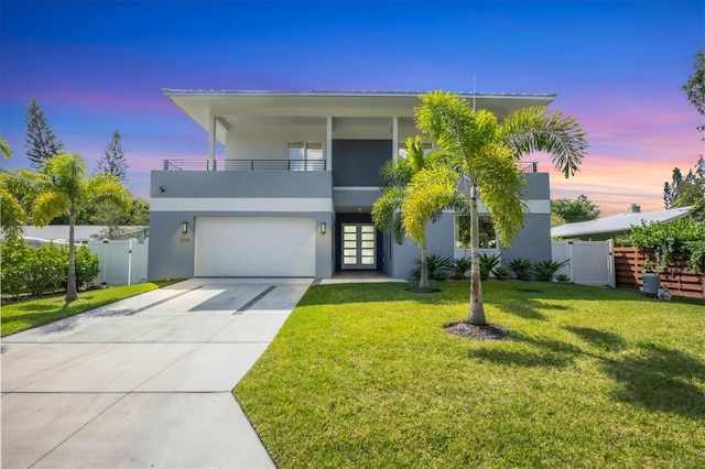 view of front of home featuring a lawn, a balcony, and a garage