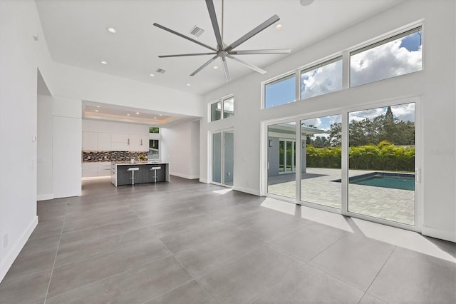 unfurnished living room with a towering ceiling, ceiling fan, and tile patterned floors