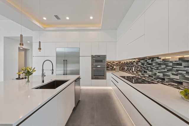 kitchen featuring appliances with stainless steel finishes, hanging light fixtures, sink, and white cabinetry