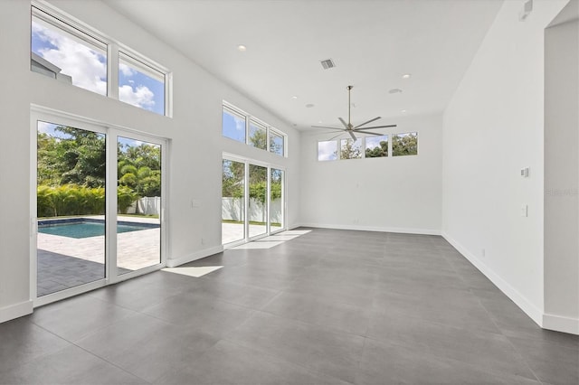 empty room with a high ceiling, ceiling fan, and concrete flooring