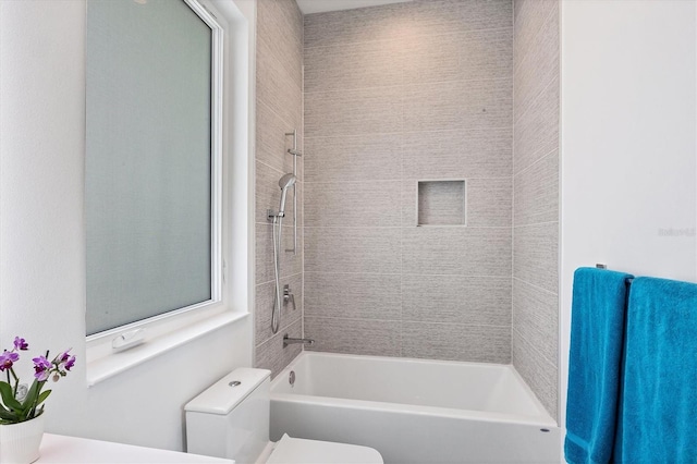 bathroom featuring tiled shower / bath and toilet