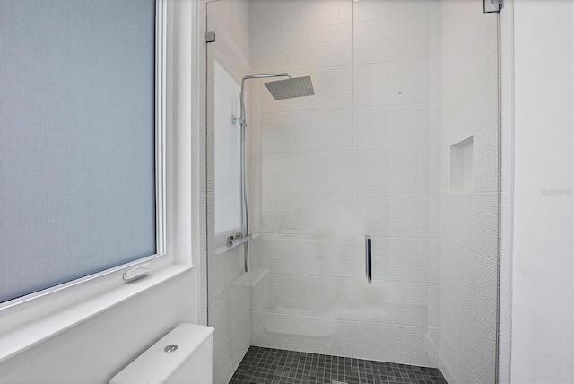 bathroom with a shower with shower door and toilet