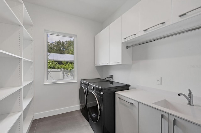 clothes washing area with cabinets, sink, washing machine and clothes dryer, and tile patterned floors