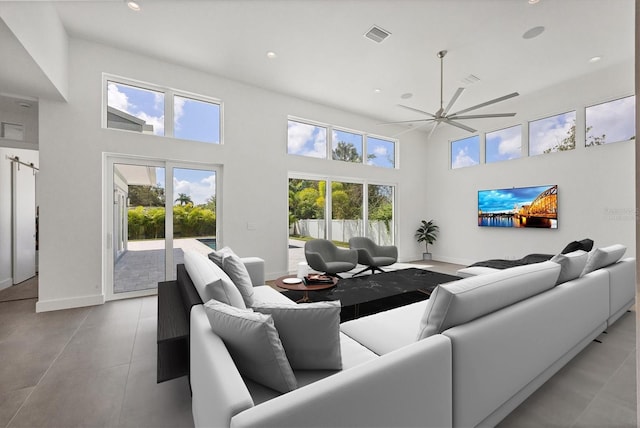 living room with a barn door, a towering ceiling, and ceiling fan