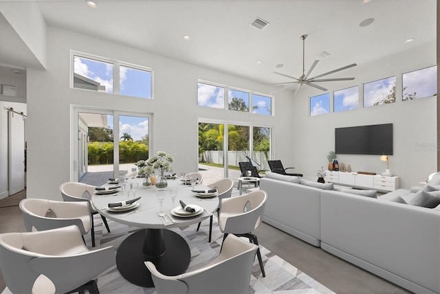 dining area featuring a high ceiling, a healthy amount of sunlight, and finished concrete floors