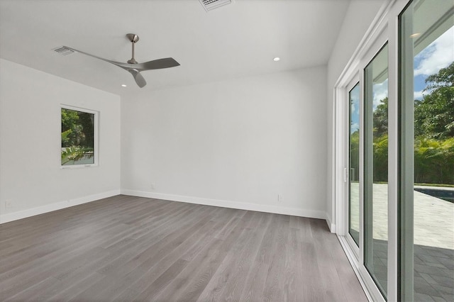 empty room with a ceiling fan, baseboards, visible vents, and wood finished floors