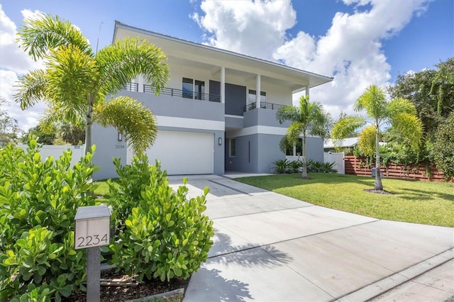 modern home featuring a garage, concrete driveway, a balcony, a front lawn, and stucco siding