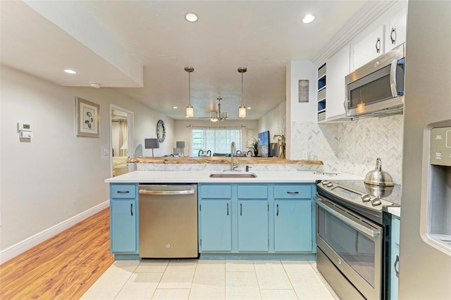 kitchen with blue cabinetry, sink, decorative light fixtures, kitchen peninsula, and stainless steel appliances