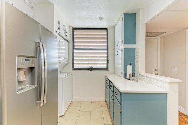 kitchen with stainless steel refrigerator with ice dispenser and stacked washer and clothes dryer