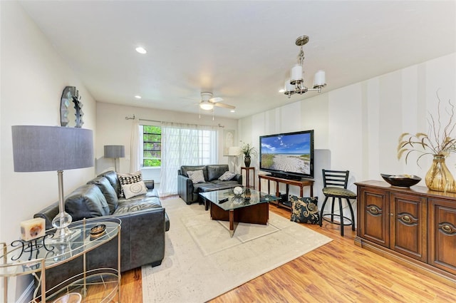 living room with ceiling fan with notable chandelier and light hardwood / wood-style flooring