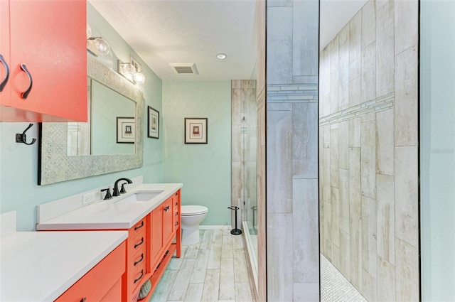 bathroom with vanity, a tile shower, and toilet