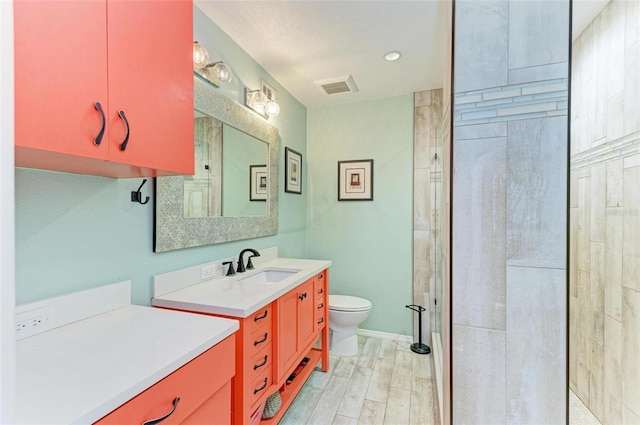 bathroom featuring a tile shower, vanity, and toilet