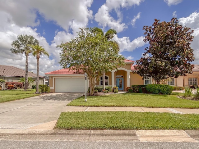 mediterranean / spanish home with stucco siding, concrete driveway, a front yard, a garage, and a tiled roof