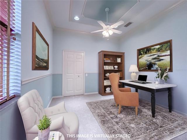 carpeted office with baseboards, visible vents, a raised ceiling, ceiling fan, and ornamental molding